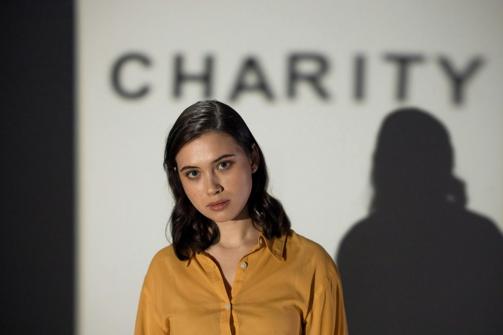 A thoughtful woman stands before a charity-themed backdrop, evoking compassion and volunteerism.
